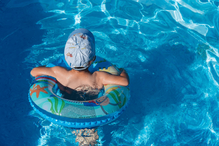 A kid in a swimming pool with a floating device